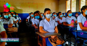 Estudiantes sentados en sus pupitres dentro del salón de clases, listos para iniciar el ciclo escolar