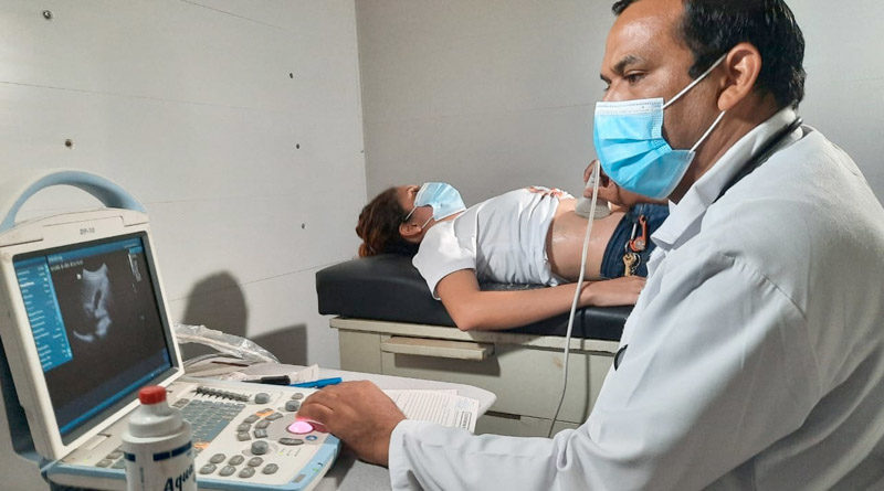 Médico del Ministerio de Salud realiza un ultrasonido a una paciente acostada en una cama