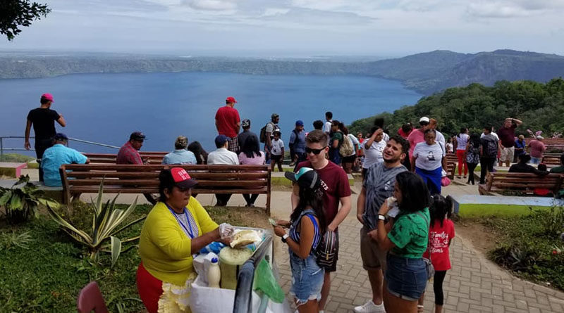 Una señora vende quesillos a un grupo de jóvenes en el mirador de Catarina