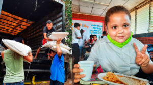 Trabajadores del Ministerio de educación descargando sacos de arroz y niña estudiante de una escuela de Masaya, Nicaragua comienda la Merienda Escolar