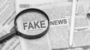 Lupa enfocando las noticias falsas en un periódico