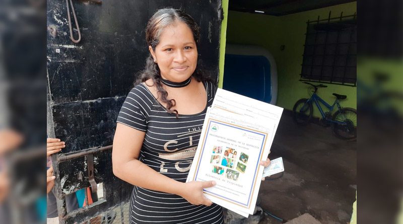 Una mujer muestra el título de propiedad recibido