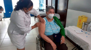 Médica del Ministerio de Salud aplica vacuna contra el Covid-19 a una señora en silla de ruedas