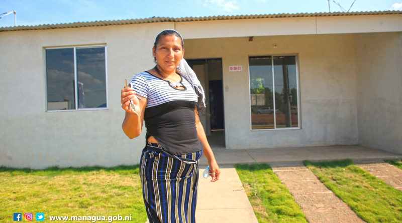Una mujer muestra las llaves de la vivienda recibida en Villa Santiago