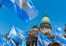 Banderas de Argentina siendo ondeadas por personas congregadas en la Plaza del Congreso de Argentina, ubicada en la Ciudad de Buenos Aires