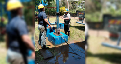 Dos hombres trabajan en el motor de la bomba de un pozo de agua