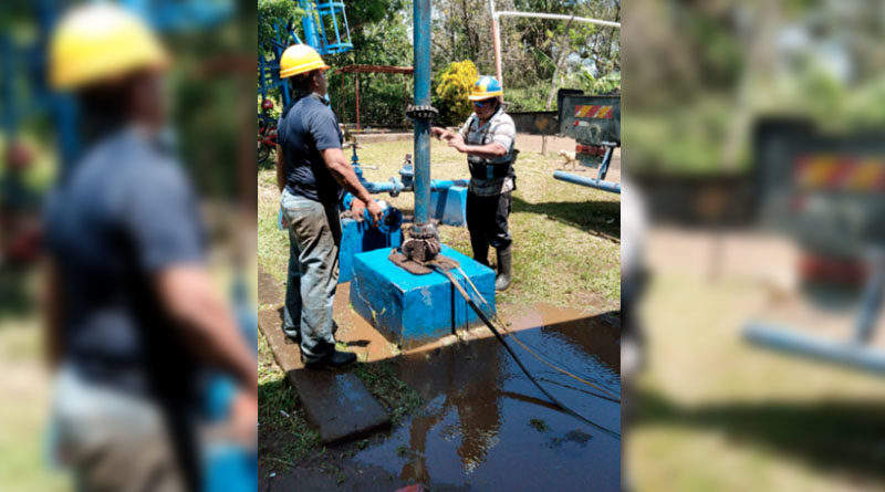 Dos hombres trabajan en el motor de la bomba de un pozo de agua