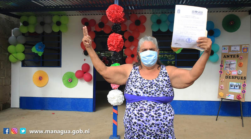 Señora que recibió la nueva vivienda, levanta las manos mostrando las llaves de su hogar