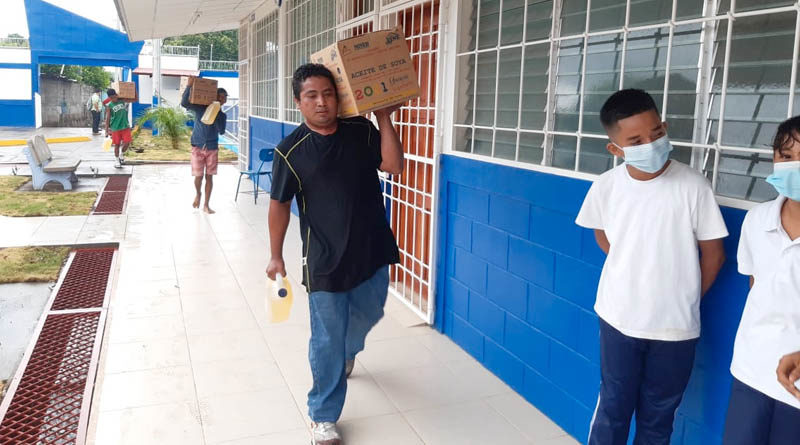 Hombres cargan cajas de aceites, parte de la Merienda Escolar entregada este martes 04 de mayo