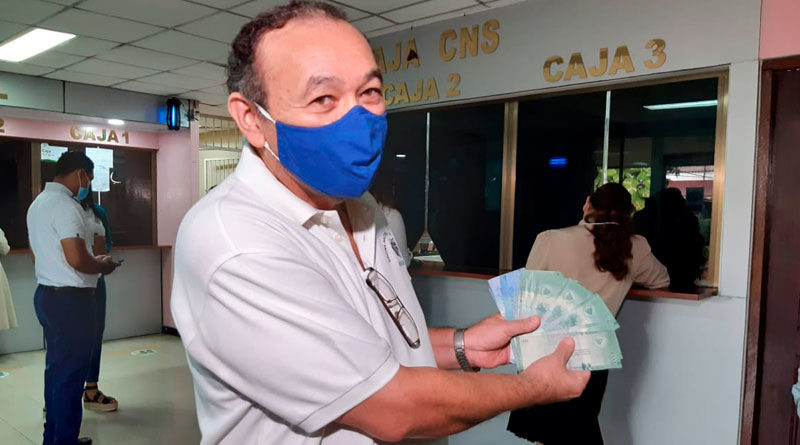 Trabajador del Ministerio de Salud mostrando su salario que acaba de retirar en unas de las cajas habilitadas en el complejo de salud Concepción Palacios de Managua, Nicaragua.