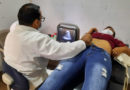 Paciente sobre una camilla es atendida por un médico, quien realiza un ultrasonido durante la feria de salud en el barrio Hiealeah