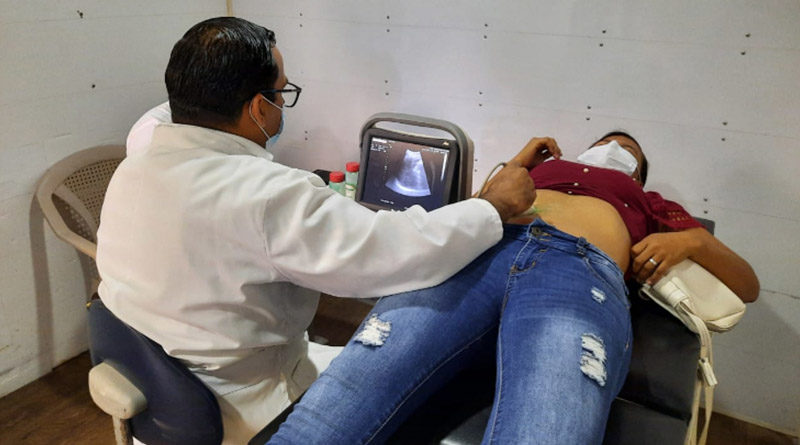 Paciente sobre una camilla es atendida por un médico, quien realiza un ultrasonido durante la feria de salud en el barrio Hiealeah