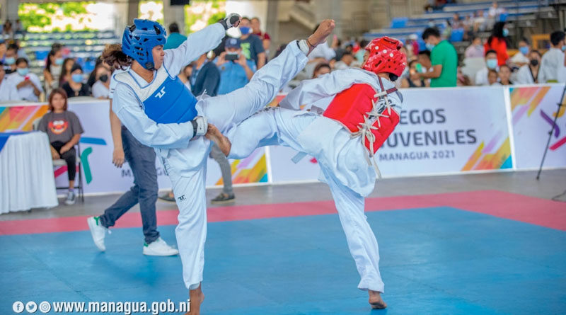 Dos jóvenes peleando durante el inicio del taekwondo en los Juegos Juveniles Managua 2021