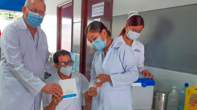 Doctor Carlos Sáenz, Secretario General del Ministerio de Salud en Nicaragua junto a una enfermera que aplica vacuna contra el covid-19 a un ciudadano