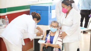 Doctoras del Ministerio de Salud vacunan a una anciana en silla de ruedas