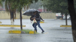 Dos personas bajo la lluvia cubriéndose con un paraguas