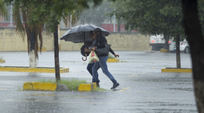 Dos personas bajo la lluvia cubriéndose con un paraguas
