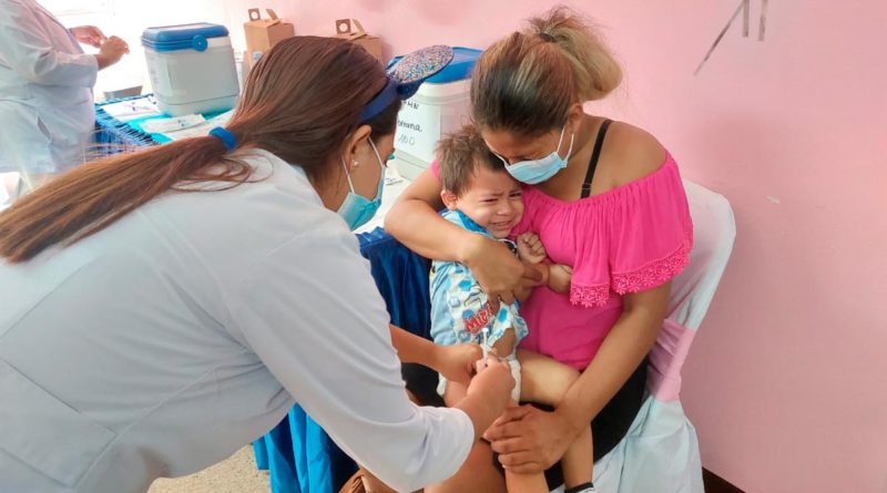 Niño en brazos de su madre siendo vacunado contra la COVID-19 por una enfermera del Ministerio de Salud de Nicaragua.