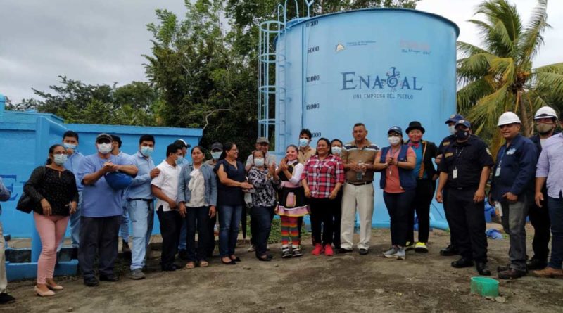 Personas delante de un tanque de agua, en la inauguración del proyecto