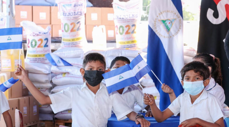 Estudiantes junto a sacos de la Merienda Escolar 2022