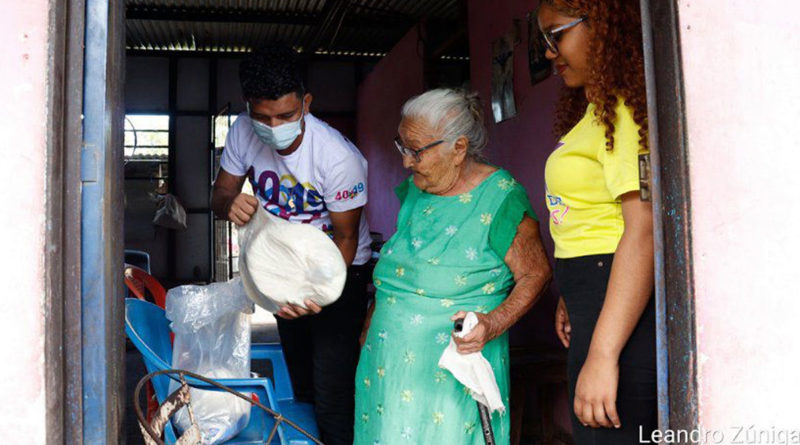 Jovenes de promotoria solidaria entregando paquetes alimenticios solidarios a madres de héroes y mártires del barrio Domitila Lugo