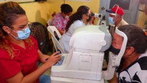 Agentes de salud en jornada especial de salud visual en el barrio 19 de Julio, realizando examen de la vista a protagonista