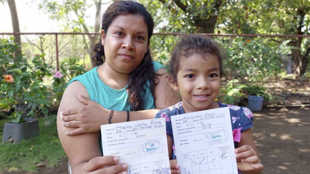 Una madre y su hija sostienen sus tarjetas de vacuna tras aplicarse una nueva dosis contra el COVID-19