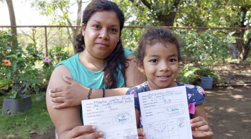 Una madre y su hija sostienen sus tarjetas de vacuna tras aplicarse una nueva dosis contra el COVID-19