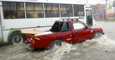 Dos vehículos pasan por una calle mientras llueve en Managua