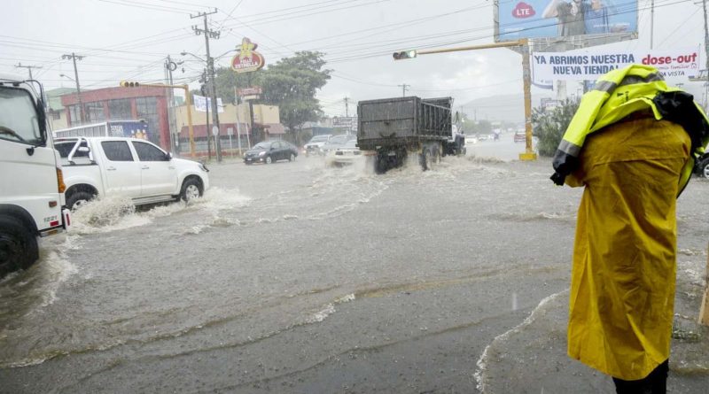 Hombre con un capote amarilla mientras llueve en una de las calles de Managua