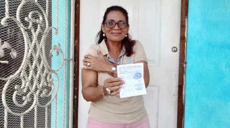 Pobladora del barrio Javier Cuadra muestra su tarjeta tras ser vacunada contra el COVID-19