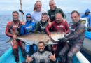 Grupo de pescadores sostienen un pez en sus manos